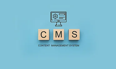 Holzwürfel mit den Buchstaben CMS, Symbolbild zum Vergleich von Content-Management-Systemen